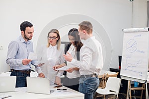 Group of four diverse men and women in casual clothing talking in office