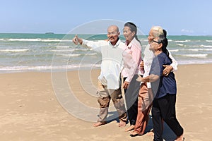 Group of four elderly old senior friends traveling outdoor together, take a selfie on mobile phone, have fun and enjoy spending