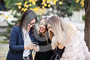 Group of four girl friends looking at phone on the selfie they w