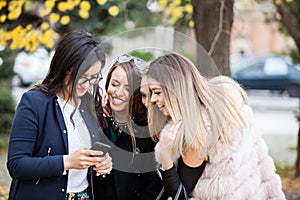 Group of four girl friends looking at phone on the selfie they w