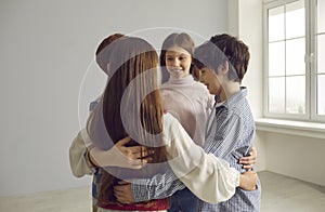 Group of four happy positive little school children hugging each other and smiling