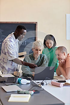Group of four intercultural students or programmers looking at laptop screen