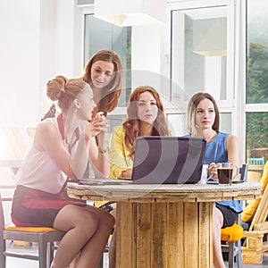 Group of four pretty businesswoman working togeather with new startup project using laptop computer in modern loft
