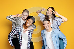 Group of Four Smiling Young Friends Posing Playfully Against Yellow