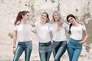 Group of diverse girls in tshirts and jeans over street wall photo