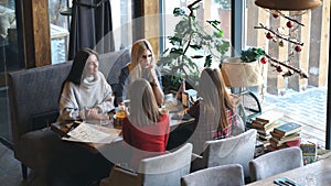 Group of four young people sitting at table in restaurant and having fun while dining.