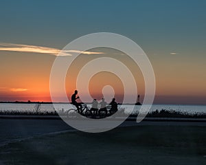 Group of four young people talking and enjoying a sunset photo