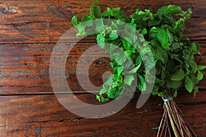 Group of fresh organic green mint on rustic wooden table. Aromatic peppermint with medicinal and culinary uses