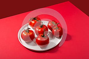 Group of fresh tomatoes on white plate red background