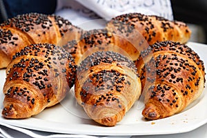 Group of freshly baked croissants decorated with chocolate chips lies on a white plate