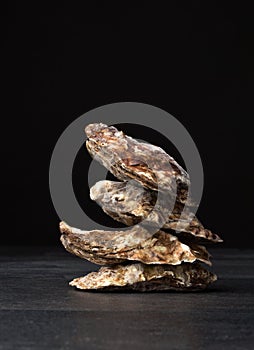 A group of freshly and raw shucked oysters on a black background. Chilled raw oysters. Delicious tropical sea mollusk.