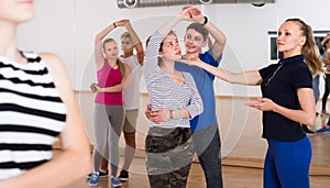 Group of friendly teenagers dancing tango in dance studio