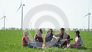 A group of friends arranged a picnic with music on a green meadow, slow motion