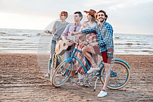 A group of friends on the beach with their bicycles