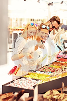 Group of friends buying jelly sweets on market