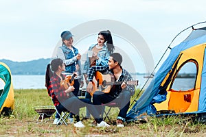 Group of friends camping and they are sitting playing guitar. Camp and music guitar concept