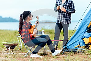 Group of friends camping and they are sitting playing guitar. Camp and music guitar concept