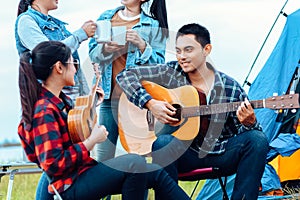 Group of friends camping and they are sitting playing guitar. Camp and music guitar concept