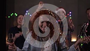 Group of friends celebrating enjoying new years eve party having fun celebration. Portrait of a curly red haired blowing