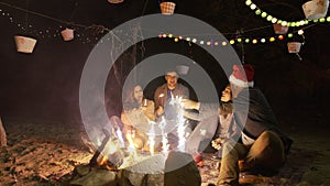 Group of friends celebrating new years eve on the beach party holding sparklers