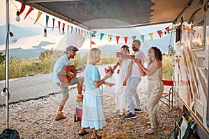 A group of friends celebrating their friends wedding at the campsite in the nature. Relationship, honeymoon, camping, nature