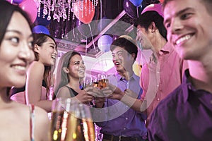 Group of friends celebrating, toasting with champagne, nightclub in Beijing