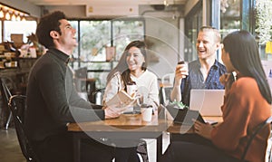 Group of friends chatting and using laptop in cafe at the coffee shop cafe in university talking and laughing together.