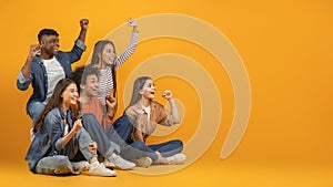 Group of friends cheering and celebrating on orange background