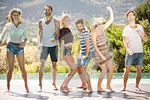 Group of friends dancing at poolside