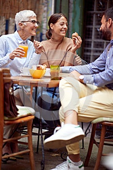 A group of friends of different generations talking while they have a drink in the bar. Leisure, bar, friendship, outdoor