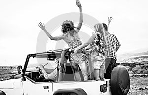 Group of friends driving off road convertible car during roadtrip - Happy travel people having fun in vacation