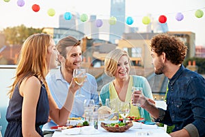 Group Of Friends Eating Meal On Rooftop Terrace