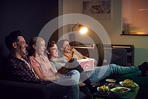Group Of Friends Eating Popcorn Sitting On Sofa At Home Watching Evening TV And Relaxing Together