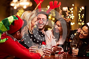 Group Of Friends Enjoying Christmas Drinks In Bar