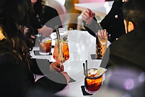 Group of friends enjoying different types of cocktails at the table of a bar.