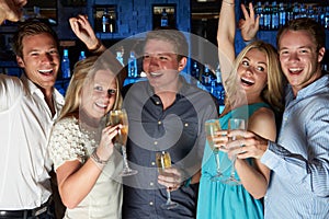 Group Of Friends Enjoying Glass Of Champagne In Bar