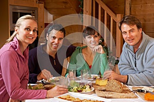 Group Of Friends Enjoying Meal In Alpine Chalet