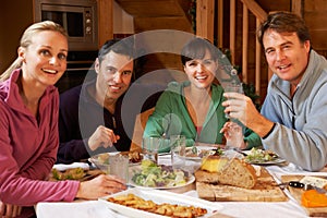 Group Of Friends Enjoying Meal In Alpine Chalet