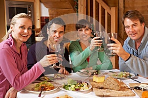 Group Of Friends Enjoying Meal In Alpine Chalet