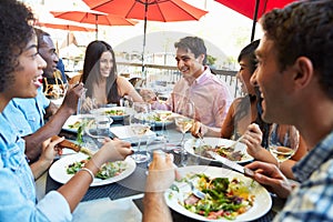 Group Of Friends Enjoying Meal At Outdoor Restaurant