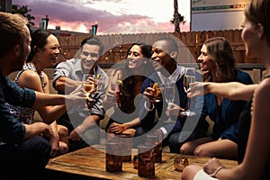 Group Of Friends Enjoying Night Out At Rooftop Bar