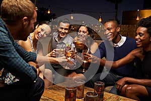 Group Of Friends Enjoying Night Out At Rooftop Bar