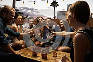 Group Of Friends Enjoying Night Out At Rooftop Bar