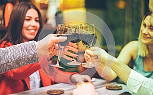 Group of friends enjoying red wine in speakeasy vintage bar - Young people hands cheering with wine and having fun hanging out -
