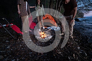 Group of friends enjoying a serene camping trip by the lakeside at twilight