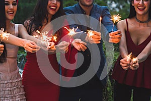 Group of friends enjoying with sparklers fireworks in the party in the evening