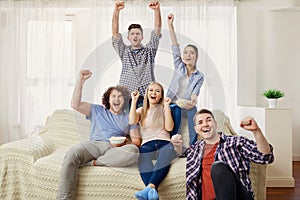 A group of friends of fans watching a sports TV sitting on a sof