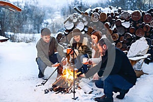 Group of friends gathering around bonfire in backyard,