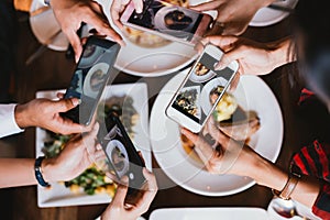 Group of friends going out and taking a photo of Italian food together with mobile phone.
