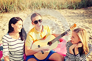 Group of friends with guitar having fun on beach